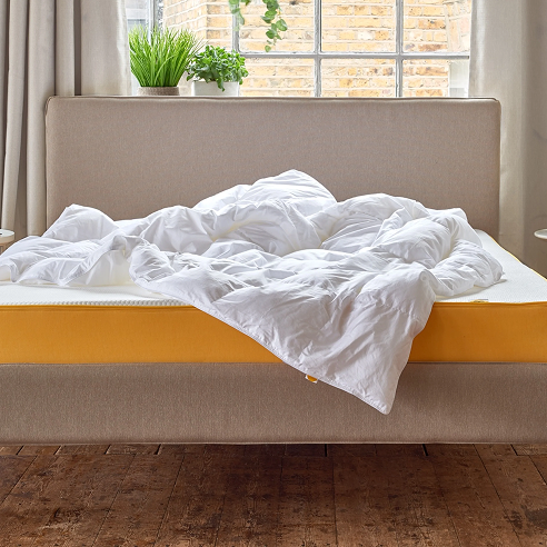 Neatly made bed with white duvet in a bright bedroom, eve sleep